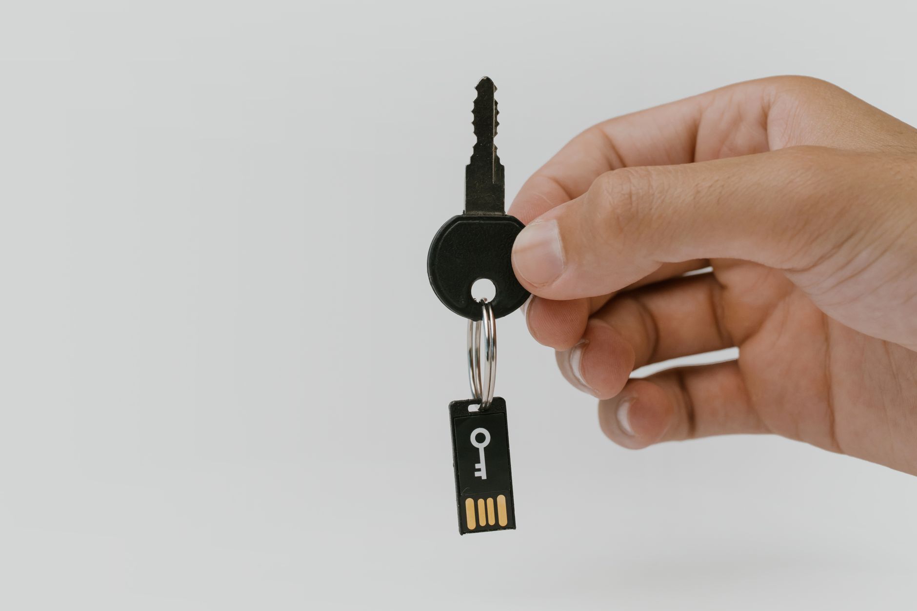 Dłoń trzymająca klucz z pendrive’em symbolizującym bezpieczeństwo danych