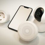 Kamera, głośnik i smartfon smart home leżące na białej powierzchni