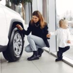 Mama z córką oglądają koło rodzinnego auta w salonie samochodowym