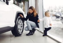 Mama z córką oglądają koło rodzinnego auta w salonie samochodowym