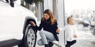 Jak bezpiecznie kupić używany samochód rodzinny: praktyczny poradnik krok po kroku Mama z córką oglądają koło rodzinnego auta w salonie samochodowym
