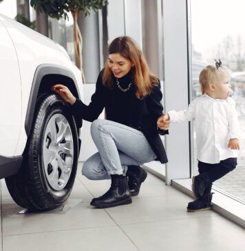 Mama z córką oglądają koło rodzinnego auta w salonie samochodowym