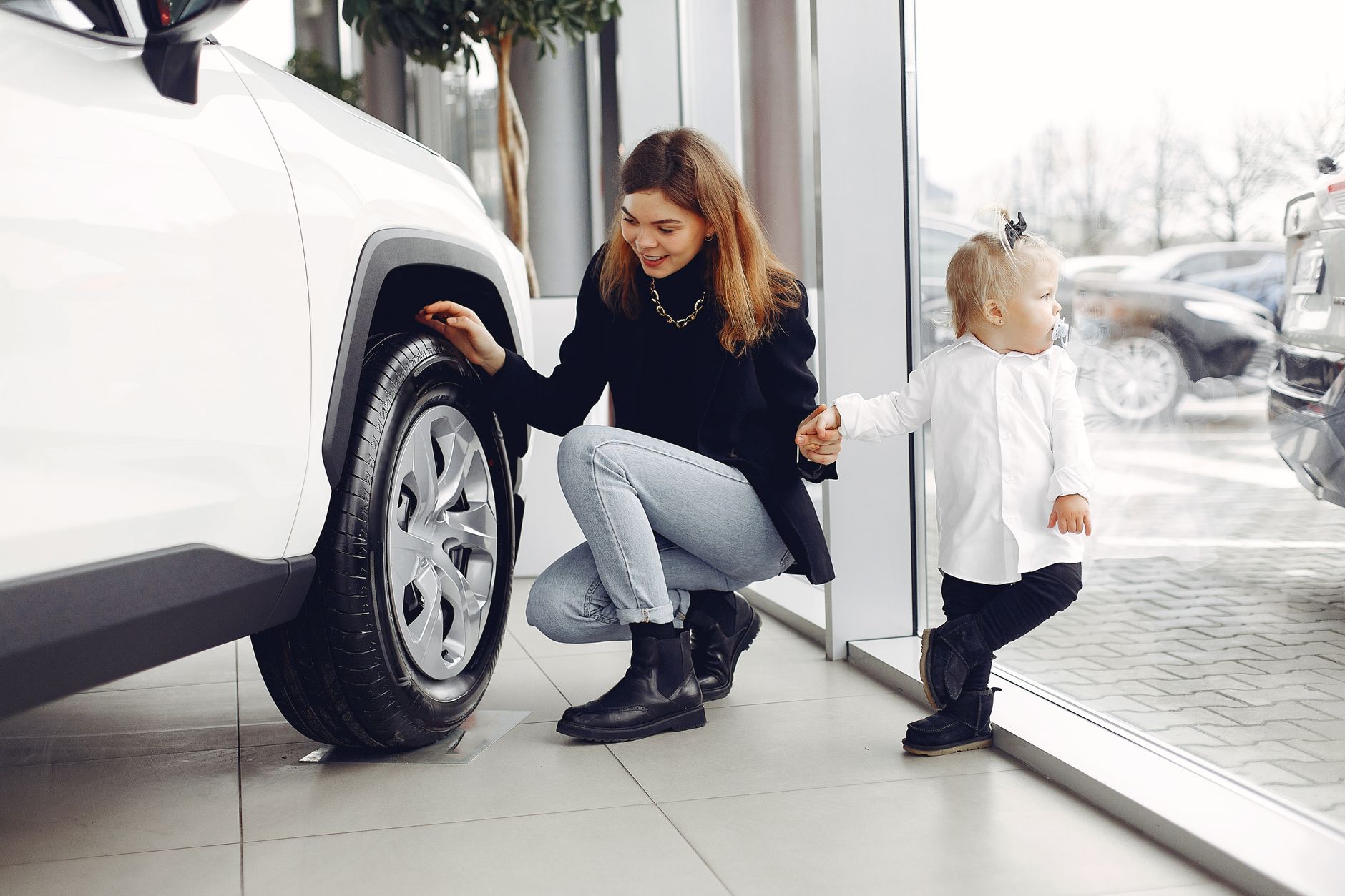 Mama z córką oglądają koło rodzinnego auta w salonie samochodowym