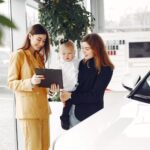 Mama z córką rozmawiają z dealerem o rodzinnym aucie w salonie