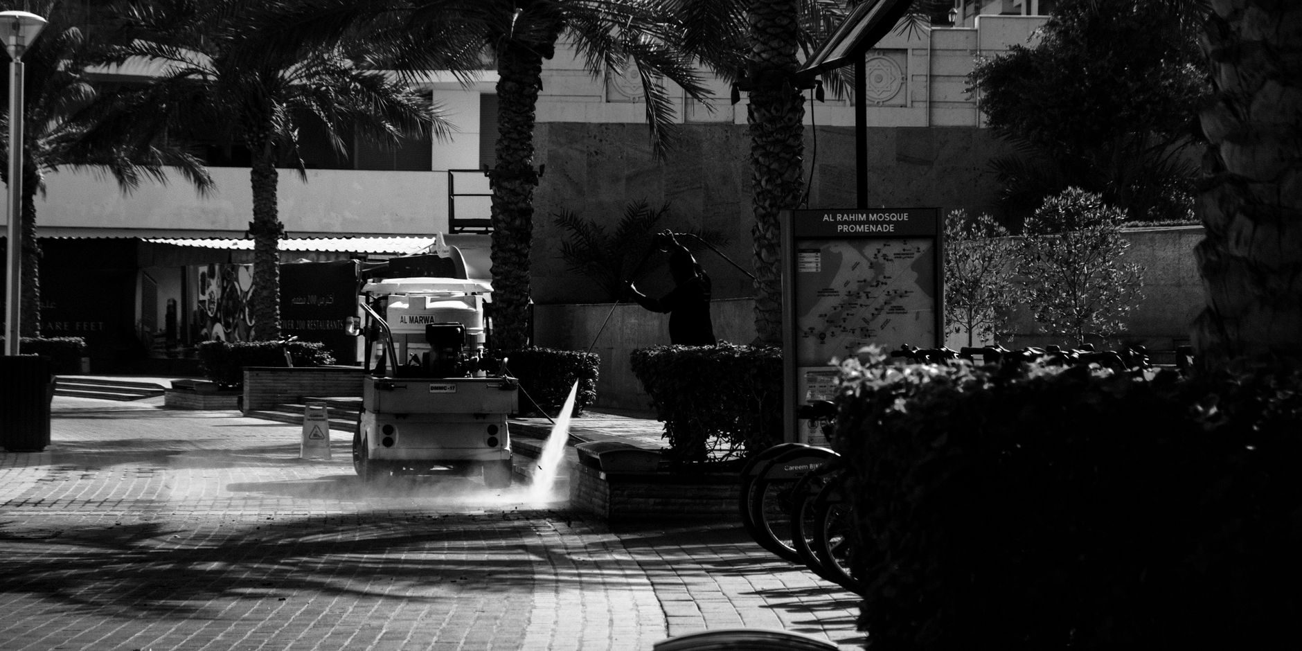 Pracownik sprzątający promenadę przy meczecie Al Rahim w Dubaju, zdjęcie b&w