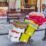 Sprzedawca uliczny w Dubaju wiezie na wózku świeże owoce i warzywa