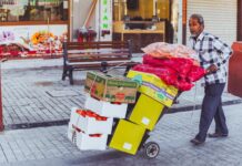 Sprzedawca uliczny w Dubaju wiezie na wózku świeże owoce i warzywa