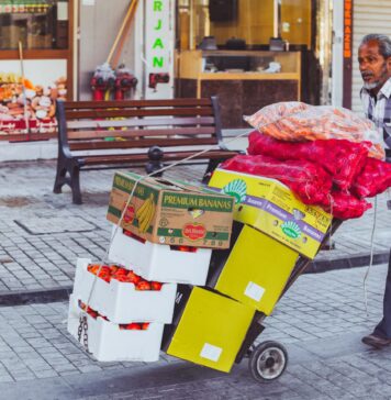 Sprzedawca uliczny w Dubaju wiezie na wózku świeże owoce i warzywa