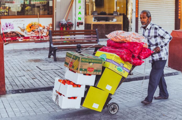 Sprzedawca uliczny w Dubaju wiezie na wózku świeże owoce i warzywa