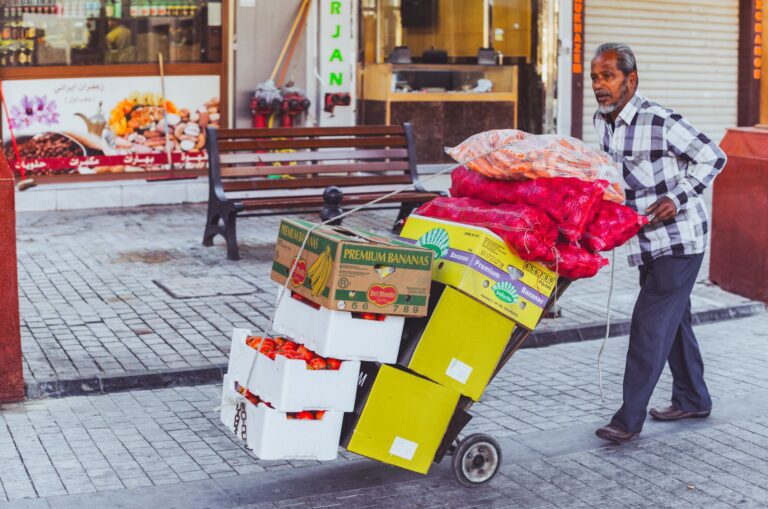 Sprzedawca uliczny w Dubaju wiezie na wózku świeże owoce i warzywa