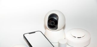 Bezpieczny smart home: konfiguracja sieci, aktualizacje i segmentacja urządzeń IoT w praktyce Zestaw urządzeń smart home z wyświetlaczem smartfona zabezpieczającego dom