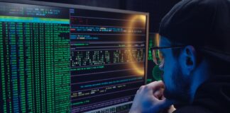 Jak przygotować pracowników na cyberataki szkolenia które naprawdę działają Pracownik analizuje kod na dwóch monitorach w ciemnym biurze