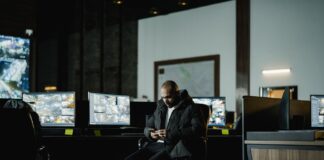 Jak pogodzić monitoring wizyjny w firmie z przepisami RODO i prawami pracowników Pracownik ochrony w ciemnej dyżurce obserwuje firmowe monitory monitoringu