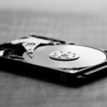 Czarno-białe ujęcie otwartego dysku twardego i jego podzespołów