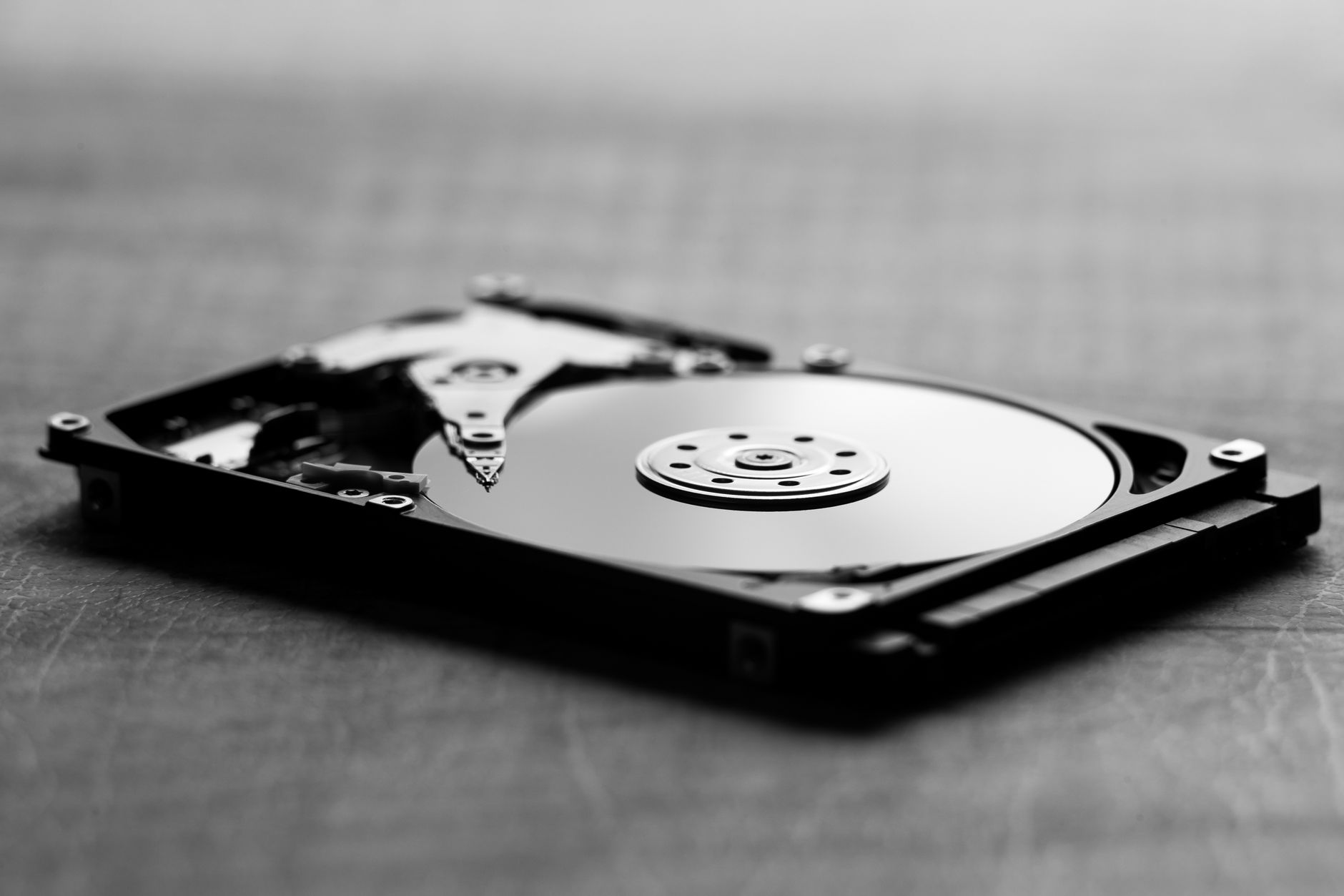 Czarno-białe ujęcie otwartego dysku twardego i jego podzespołów