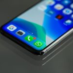Ekran smartfona z ikonami komunikatorów, w centrum ikona WhatsApp
