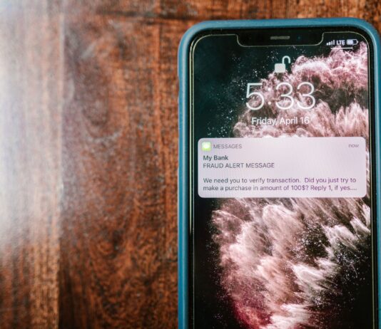 Smartfon na drewnianym stole z powiadomieniem o próbie oszustwa