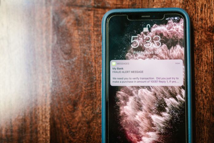 Smartfon na drewnianym stole z powiadomieniem o próbie oszustwa Smartfon na drewnianym stole z powiadomieniem o próbie oszustwa
